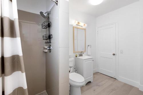 a white bathroom with a toilet and a mirror at Victoria Park Unique Studio close to Las Olas Blvd in Fort Lauderdale