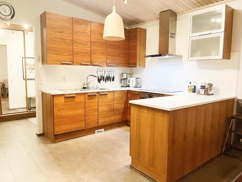 a large kitchen with wooden cabinets and a sink at Nordic Villa with private sledding hill in Rovaniemi