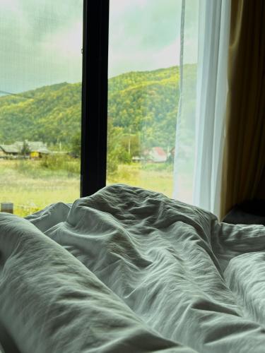 an unmade bed next to a window with a view at Rest гори 360 чан форель харчування in Sheshory