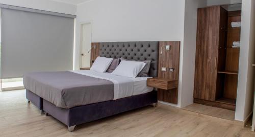 a bedroom with a large bed with a gray headboard at Silver Inn Hotel in Cerro Azul