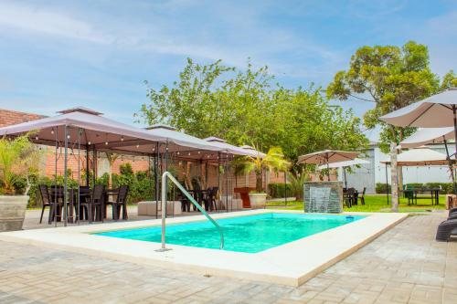 a swimming pool with umbrellas and a table and chairs at Silver Inn Hotel in Cerro Azul