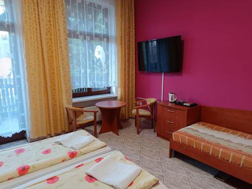 a hotel room with two beds and a flat screen tv at Dom Wczasowy Magnolia in Lądek-Zdrój