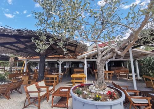 a patio with tables and chairs and a tree at Anamaria in Kaštela