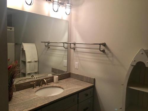 Un baño con lavabo y un espejo grande. en New Ocean Block Duplex, en Beach Haven