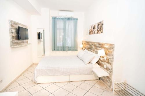 a bedroom with a bed and a tv on a wall at Taormina Beach House in Mazzeo