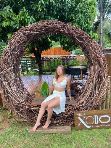 a woman is sitting in a large wicker arch at Villa Xodó in Fernando de Noronha