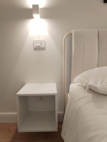 a white nightstand next to a bed with a light at Ciliegia di Lari - Attico in Lari