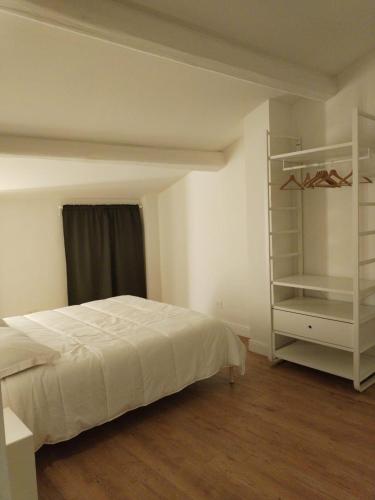 a bedroom with a white bed and a shelf at Ciliegia di Lari - Attico in Lari