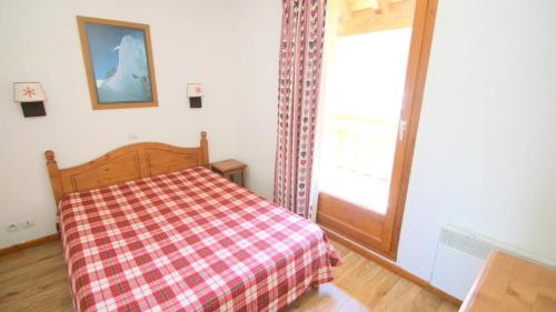 1 dormitorio con 1 cama con manta a cuadros y ventana en Résidence Parc Aux Etoiles - CH15PAE - CHALET DUPLEX 2 CHAMBRES, TERRASSE ET BALCON MAE-2194, en Narreyroux