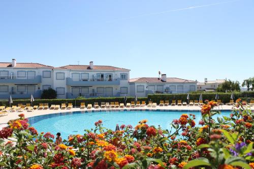 a pool with chairs and flowers in front of a building at Oásis Parque Portimão in Portimão