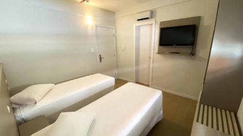 a small room with two beds and a tv at ÓPER SMART HOTEL in Santa Maria