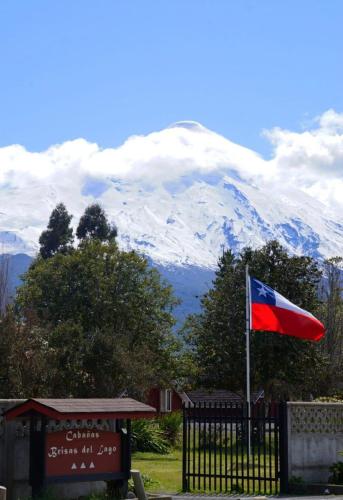 a flag flying in front of a snow covered mountain at Cabañas Brisas Del Lago in Puerto Varas