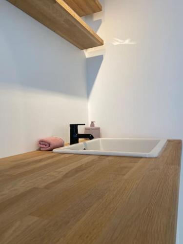 a room with a white tub in a room with a wooden floor at The Conservatory a cosy little holiday home- central between Gent Antwerpen Brussel & Brugge in Lokeren