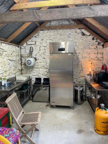 a kitchen with a refrigerator in a stone wall at Glamping at The Old Rectory in Dún Ard