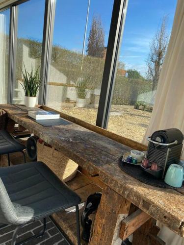 a wooden table with a chair in front of a window at The Conservatory a cosy little holiday home- central between Gent Antwerpen Brussel & Brugge in Lokeren