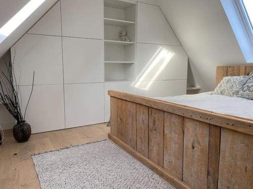 a bedroom with a wooden bed and white walls at The Conservatory a cosy little holiday home- central between Gent Antwerpen Brussel & Brugge in Lokeren