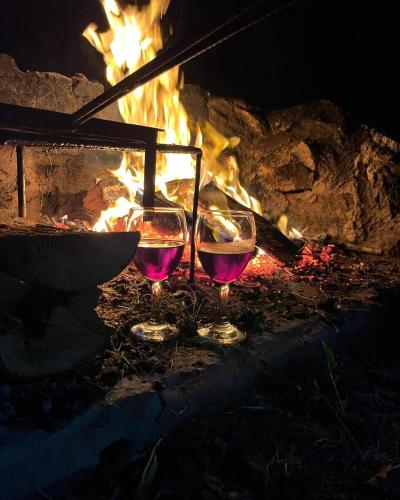 two glasses of wine sitting in front of a fire at La Luna, casa mágica en sierras! in Villa Serrana