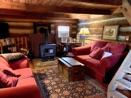 a living room with red couches and a wood stove at Heartstone Country Retreat in Buena Vista