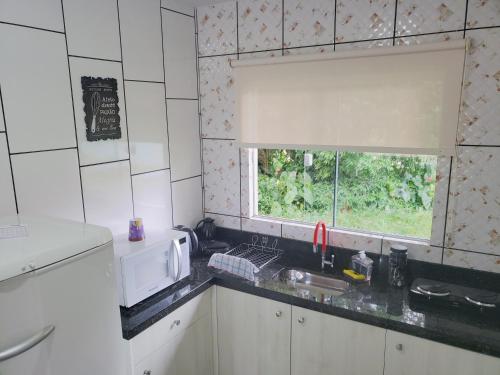 uma cozinha com um lavatório e uma janela em Casa Completa da Magui - 02 em Pomerode