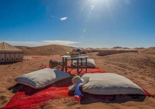 a group of pillows on a blanket in the desert at Amazing Luxury Camp in Merzouga