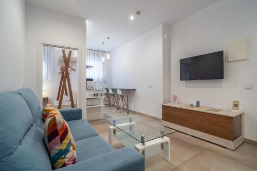 uma sala de estar com um sofá azul e uma televisão em Apartamentos CMDreams Gold- ruinas romanas a tus pies- parking privado em Mérida