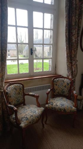 2 chaises assises devant une fenêtre dans l'établissement Gite du Manoir des Anoteux, à Carneville