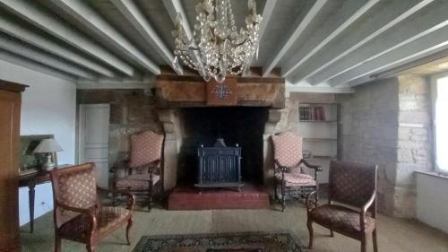 un salon avec une cheminée, des chaises et un lustre dans l'établissement Gite du Manoir des Anoteux, à Carneville