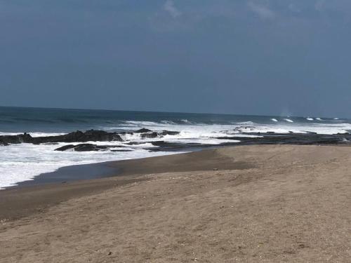 a sandy beach with waves in the ocean at Hotel Villa Ordonez in Pochomil