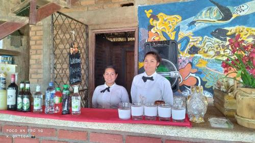 two people are standing behind a table with drinks at Hotel Villa Ordonez in Pochomil