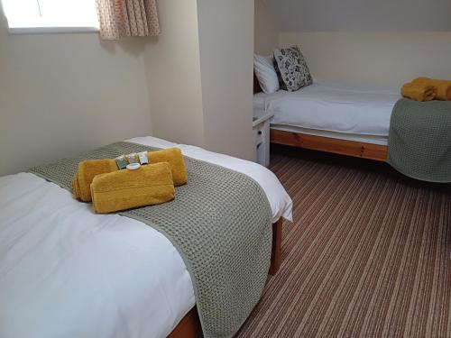 um quarto com duas camas com toalhas amarelas em Acorn Cottage, Ashover em Ashover