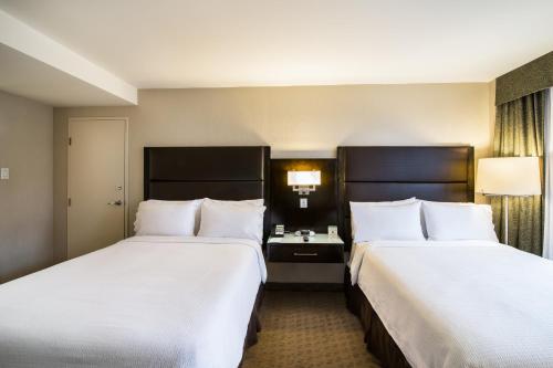 two beds in a hotel room with white sheets at Holiday Inn Vancouver-Centre Broadway by IHG in Vancouver