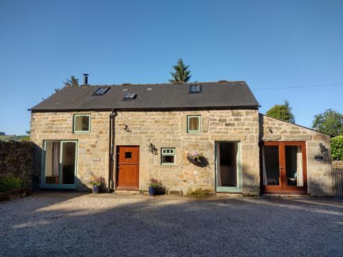 a stone house with orange doors on a driveway at Acorn Cottage, Ashover in Ashover