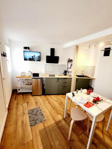 ein Wohnzimmer mit einem weißen Tisch und eine Küche in der Unterkunft Maison cosy au calme proche sanctuaire in Lourdes