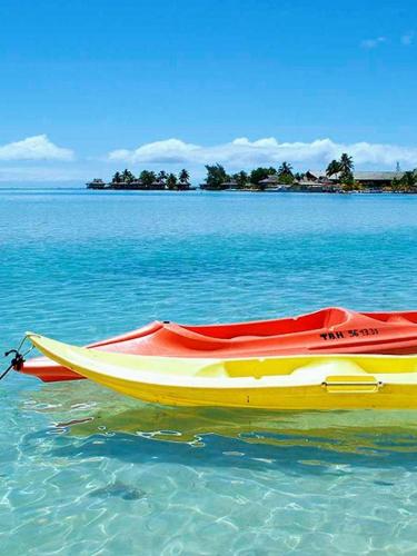 a red and yellow boat sitting in the water at Duplex en bord de mer Fare Tahitea Pension in Taputapuapea
