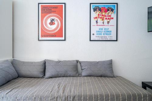 trois affiches de films encadrées sur un mur blanc avec un canapé dans l'établissement Le calme à Nissa la Bella, à Nice