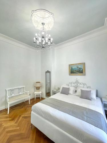 a white bedroom with a large bed and a chandelier at Stile Libero Guest House in Turin