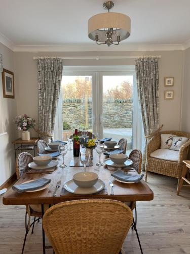 a dining room table with chairs and a large window at Anglesey Coastal Cottage 200 metres from Beach, Dog and Family Friendly in Trearddur