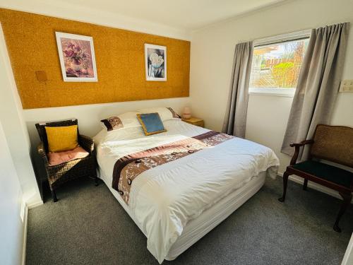 a bedroom with a bed and a chair and a window at Delight at Golf in Auckland