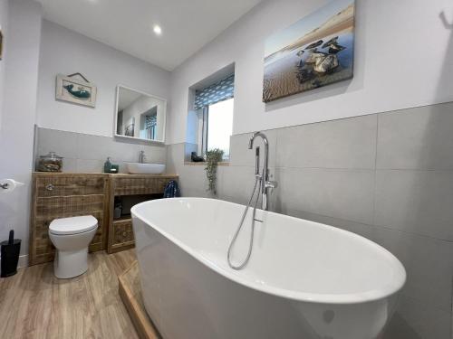 a bathroom with a white tub and a toilet at Church View Anglesey in Trearddur