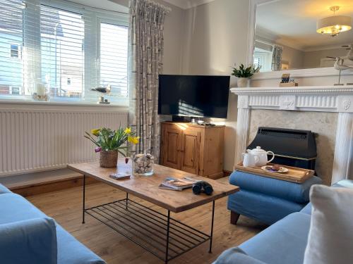 a living room with a table and a fireplace at Anglesey Coastal Cottage 200 metres from Beach, Dog and Family Friendly in Trearddur
