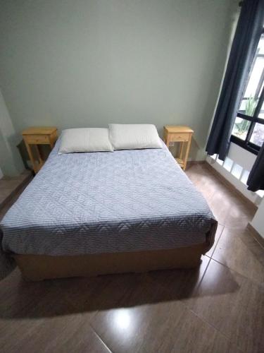 a bed in a bedroom with two windows at Depto Otero in San Salvador de Jujuy