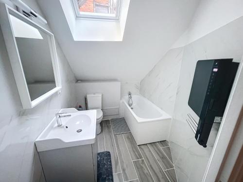 Baño blanco con lavabo y espejo en Appartement au centre-ville, en Chaumont