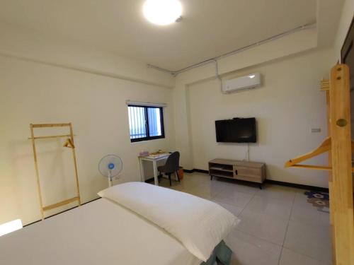 a bedroom with a bed and a flat screen tv at Caiteng B&B in Zhongli