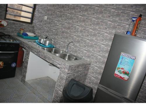 eine Küche mit einer Spüle und einem Kühlschrank in der Unterkunft Maison d'hôte avec paillote in Palimé