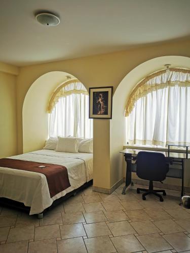 Un dormitorio con una cama y un escritorio en una habitación. en Hotel Bombonaje, en Rioja