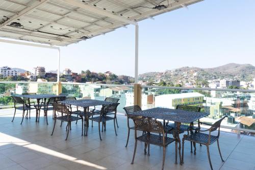 a patio with tables and chairs and a view of a city at Fabuloso Hotel Las Vegas in Zihuatanejo
