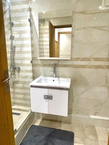 a bathroom with a white sink and a mirror at New Luxurious apartment Agdal Rabat center in Rabat