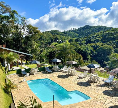 a swimming pool with chairs and umbrellas in a resort at Pousada Verdes Alpes in Santo Antônio do Pinhal