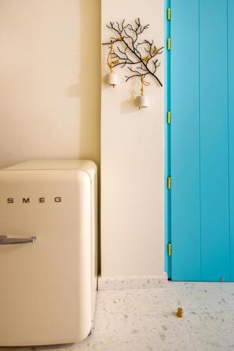 a refrigerator in a room with a blue door at Aegean Stories pelagos suites in Avlákia