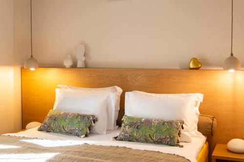 a bed with white pillows and a wooden headboard at Aegean Stories pelagos suites in Avlákia